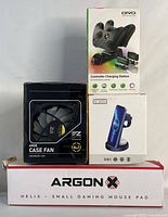 Full lot arranged showing the gaming mousepad in box at bottom, ARGB case fan box on left and controller charging station box on top right, plus the 3-in-1 wireless charging station box.