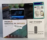 Four boxed electronic items: ITOMA digital alarm clock, ITOMA essential oil diffuser, SIMJAR key finder set, and Leviton plug-in smart outlet with Z-Wave technology.