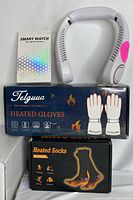 Lot contents showing the smart watch box, Telawa heated gloves box, heated socks box, and a white wearable neck fan device.