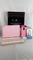 Full lot photo showing all items: wooden wireless charging dock, pink tablet cover with keyboard, pink smartphone case, white wireless mouse box, charging block, and charging cable.