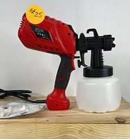 Front-side view of red and black electric paint sprayer with white translucent paint container, power cord coiled beside it, and #25 sticker on the handle.