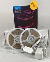 Two rolls of Govee RGB LED strip lights coiled on circular white spools. Includes white inline remote control with three buttons and a white power adapter with US plug. Govee branding visible on a label attached to the strip.