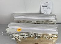 Photo showing multiple LED light bars stacked, with power cords and a manual behind them on a wooden surface.