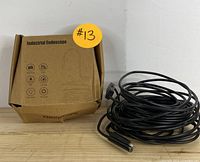 Cardboard box labeled 'Industrial Endoscope' next to coiled long black cable with camera end.
