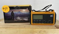 Front view of emergency weather radio with digital display, control buttons, and packaging box with feature highlights.