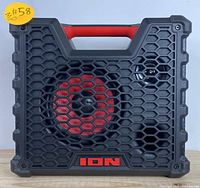 Front view of the ION portable Bluetooth speaker showing black rugged housing with hexagonal grille and red speaker.