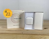 Photo showing the charging case inside original box with circular branding on box front.