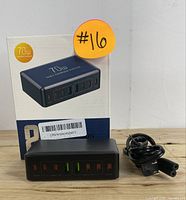 Photo of the charging station with its packaging box and power cord, showing the front with eight USB ports.