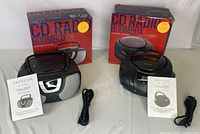 Two Proscan CD radio boomboxes side by side with boxes, power cords, and manuals.