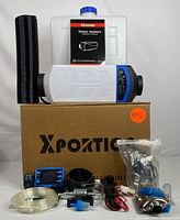Full kit components arranged showing heater, fuel tank, control panel, ducting, tubes, wiring, and accessories on a cardboard box with Xportio label.