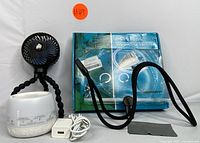 Full view of all items in the set: flexible tripod fan, white noise machine with charger, and hands-free magnifier with neck strap and cleaning cloth.