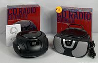 Photo showing two boxed CD radio boomboxes with their original packaging and user manual visible.