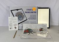 Photo of boxed lithium battery tracing light pad with instruction manual, USB cable, and transparent tracing sheets featuring fly illustrations.