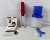 Full bundle showing digital timer with box and accessories, red handheld frother on stand, and water filter components laid out