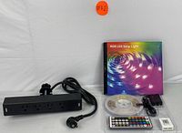 RGB LED strip light package with remote control and black desk clamp power strip.