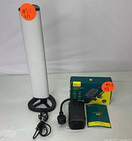 Photo of LED floor lamp standing next to outdoor smart plug with power cord and original box