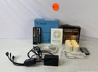 Full set of LED strip lighting kit with remote, power adapters, and user manual alongside the six flameless LED candles with charging cables and remote controls.