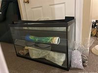 Front view of empty glass fish tank with items inside showing size and condition