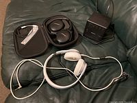 Overview of all items on couch: Bose headphones in case, Beats Solo headphones, and Sony alarm clock radio