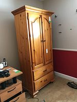Full view of tall pine cabinet showing front with two doors and two drawers.