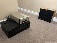 Yamaha CDC-E500 silver CD changer, Kenwood black audio receiver, and Mirage wood veneer speakers shown from side angle
