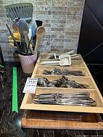 Photo of plastic drawer organizer holding various stainless steel cutlery pieces divided by type