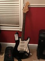 Full view of the black Squier Strat style electric guitar showing body and headstock.
