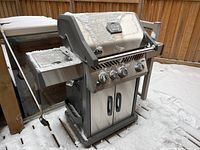 Front view of grill with hood closed showing control knobs, thermometer and doors