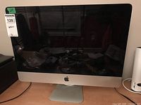 Front view of Apple iMac computer powered off, model A1311 with 21.5-inch screen, showing Apple logo on front.