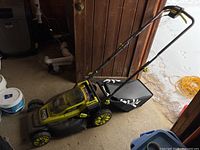 Full side view of Ryobi electric lawn mower with grass catcher attached and handle folded upright.