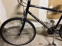 Partial side view of black Rocky Mountain Cardiac bike showing front wheel, frame, and pedals.