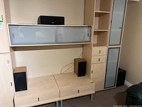 Four piece Mirage speaker set displayed on wooden furniture, includes two bookshelf speakers, one center speaker and one subwoofer.