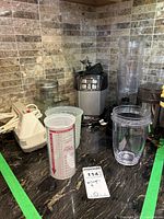 Ninja blender base unit, two clear plastic blending pitchers, and measuring cups on kitchen counter.