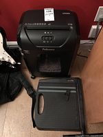 Fellowes 1200C shredder standing next to X-Acto paper trimmer on floor against wall and cabinet