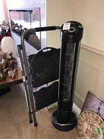 Photo of Cosco step ladder and Seville Classics tower fan side by side against wall.