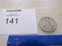 Photo of the 1917 Standing Liberty half dollar coin with a ruler for scale and auction lot number.