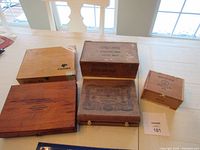 Overview of all five wooden vintage cigar boxes placed on a table showing different brands and sizes.