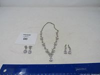 Full view of necklace with two pairs of matching earrings on a light background with ruler for scale.