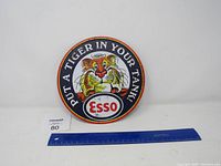 Front view of the Esso metal round sign showing the tiger and slogan text with ruler for size reference.