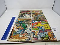 Four vintage Superman comic books laid flat showing cover art, used condition