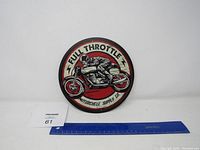 Front view of the circular metal sign showing the motorcycle graphic and text