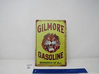 Full front view of Gilmore Gasoline metal sign featuring roaring tiger face with wording; visible minor rust and wear indicating used condition.