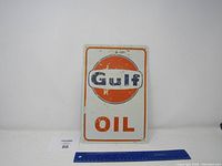 Front view of the rectangular Gulf Oil metal sign showing logo and text with surface wear and paint chipping.