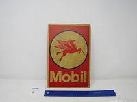 Front view of the rectangular metal Mobil sign with red border and beige circle containing the red Pegasus and 'Mobil' text.