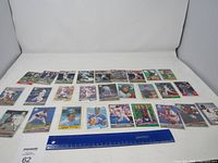 Wide shot of approximately 28 vintage baseball cards spread out with a ruler for scale.