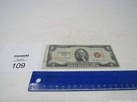 Photo showing the full $2 bill from 1953 alongside a blue ruler measuring approximately 6.3 inches and a MaxSold lot number card for scale.