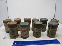 Eight vintage Edison wax cylinder phonograph records in original cardboard containers with various labels, showing wear and aged character.