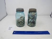 Overview photo of two blue Ball mason jars filled with seashells and small marine items, with a ruler showing size