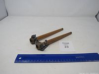 Two tapered wooden candle molds lying flat next to a blue ruler measuring approximately 12 inches.