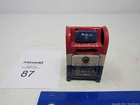 Front view of the U.S. Mail metal coin bank showing mail slot, painted details, and keyhole.